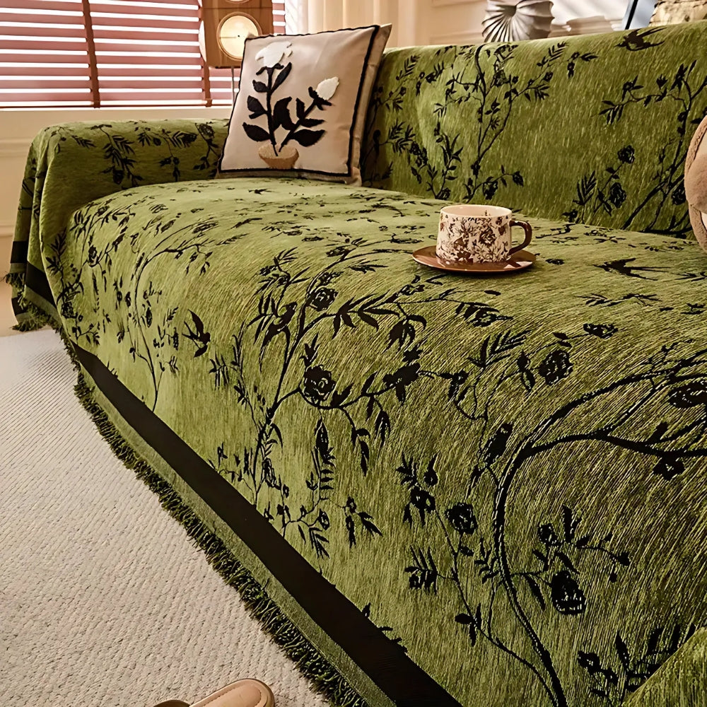 Green sofa cover with black floral pattern and fringed edges, decorative couch protector for living room