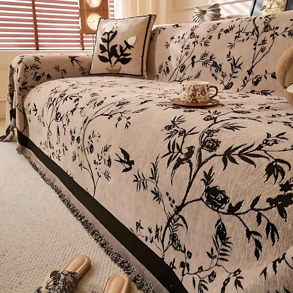 Green sofa cover with black floral pattern and fringed edges, decorative couch protector for living room