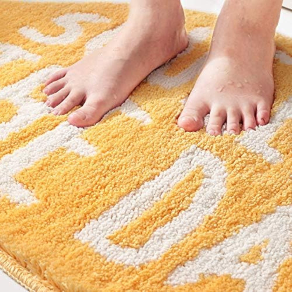 Yellow lemon-shaped bathroom rug with white text ‘Squeeze the Day’, soft absorbent bath mat