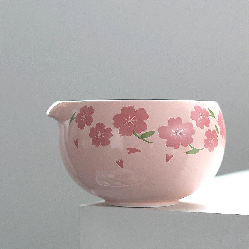 Japanese matcha tea set with pink cherry blossom bowl, bamboo whisk, sifter, and spoon for traditional green tea ceremony