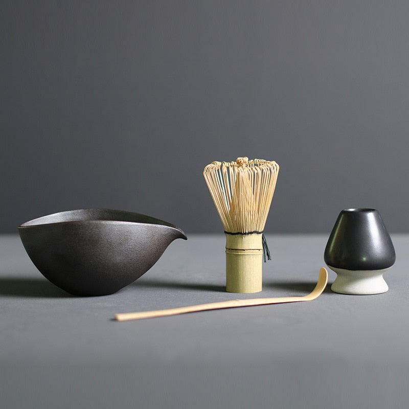 Minimalist Japanese matcha set with black ceramic tea bowl, bamboo whisk, whisk holder, and bamboo tea scoop for authentic tea ceremony
