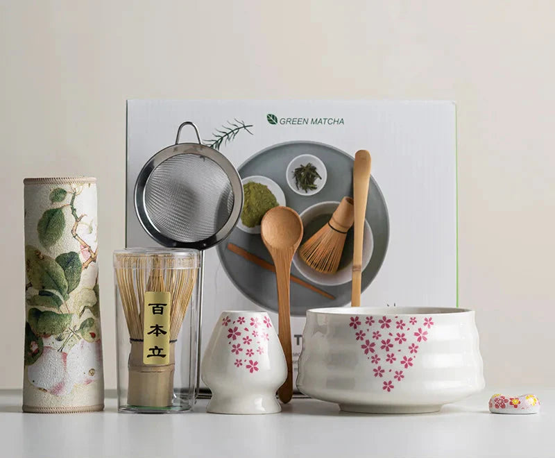 Japanese matcha set with white ceramic tea bowl and pink cherry blossom design, bamboo whisk, sifter, and tea scoop for traditional tea ceremony