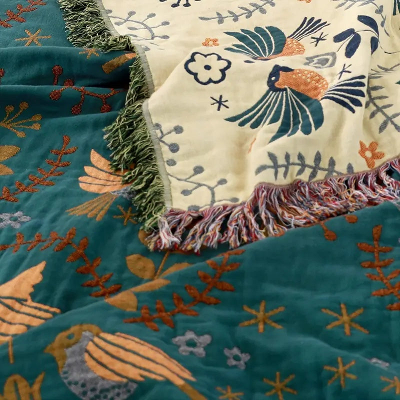 Bohemian sofa throw blanket with teal background, bird and floral patterns, and fringe edges, decorative couch cover for living room