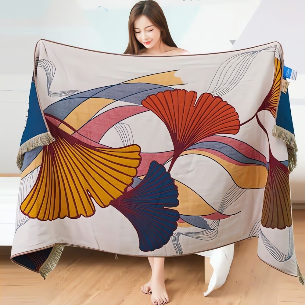 Soft decorative throw blanket with bold abstract ginkgo leaf pattern in orange, blue, and yellow, finished with tassel edges