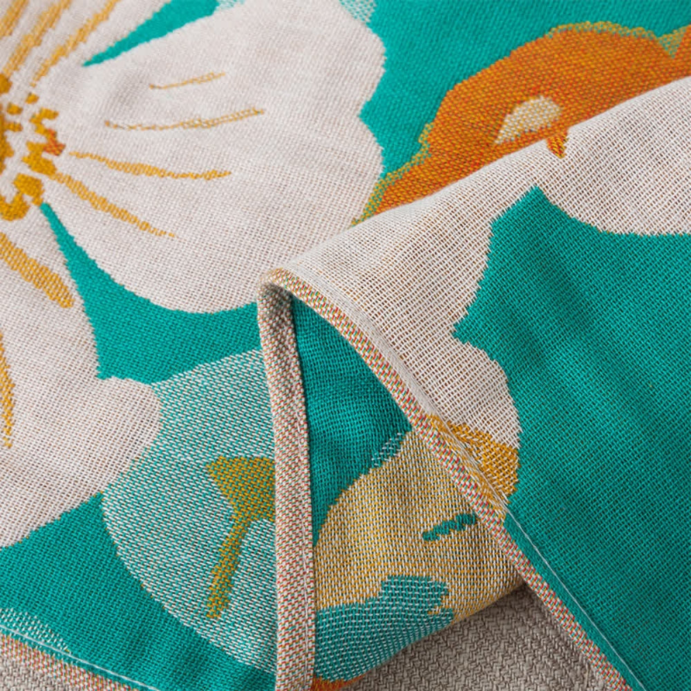 Floral throw blanket with white and orange flower design on teal background, soft decorative sofa and bed cover