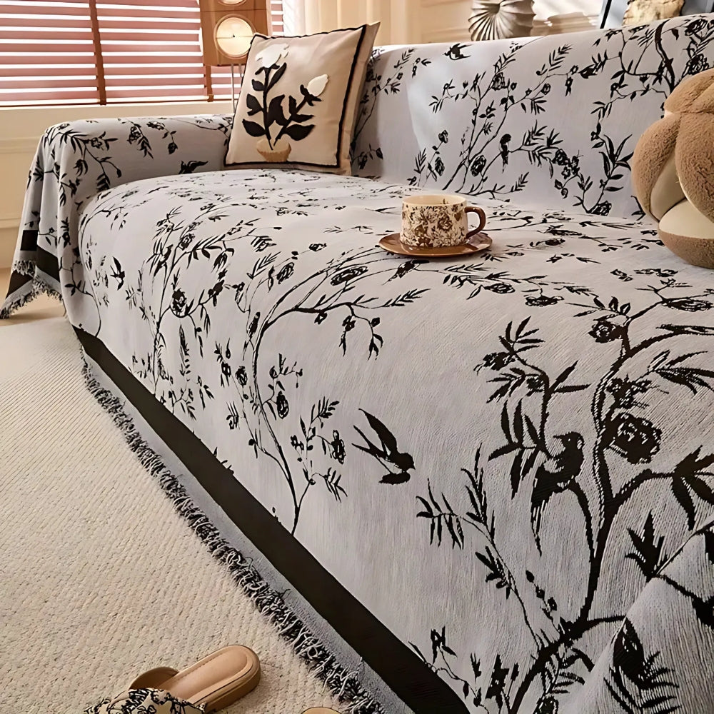 Green sofa cover with black floral pattern and fringed edges, decorative couch protector for living room