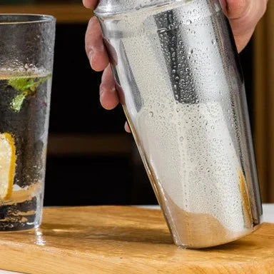 Premium stainless steel cocktail shaker set with mixing spoon, citrus slices, and bar tools – professional bartender kit for home and party drinks
