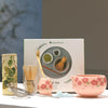 Japanese matcha tea set with pink cherry blossom bowl, bamboo whisk, sifter, and spoon for traditional green tea ceremony