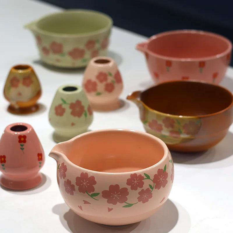 Japanese matcha tea set with pink cherry blossom bowl, bamboo whisk, sifter, and spoon for traditional green tea ceremony
