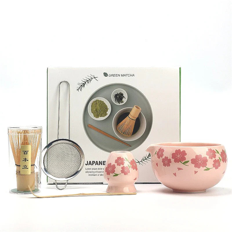 Japanese matcha tea set with pink cherry blossom bowl, bamboo whisk, sifter, and spoon for traditional green tea ceremony