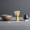 Minimalist Japanese matcha set with black ceramic tea bowl, bamboo whisk, whisk holder, and bamboo tea scoop for authentic tea ceremony