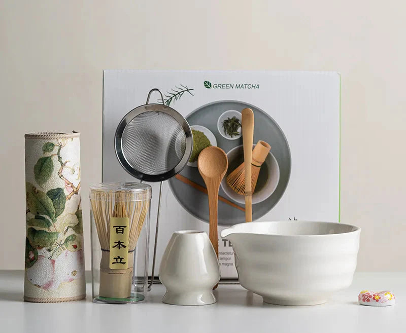Japanese matcha set with white ceramic tea bowl and pink cherry blossom design, bamboo whisk, sifter, and tea scoop for traditional tea ceremony