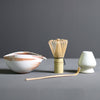 Minimalist Japanese matcha set with black ceramic tea bowl, bamboo whisk, whisk holder, and bamboo tea scoop for authentic tea ceremony