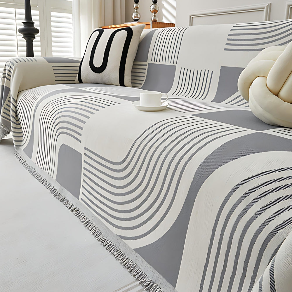 Modern geometric grey and white sofa cover with abstract wave pattern and fringe edges – washable couch slipcover for living room furniture protection