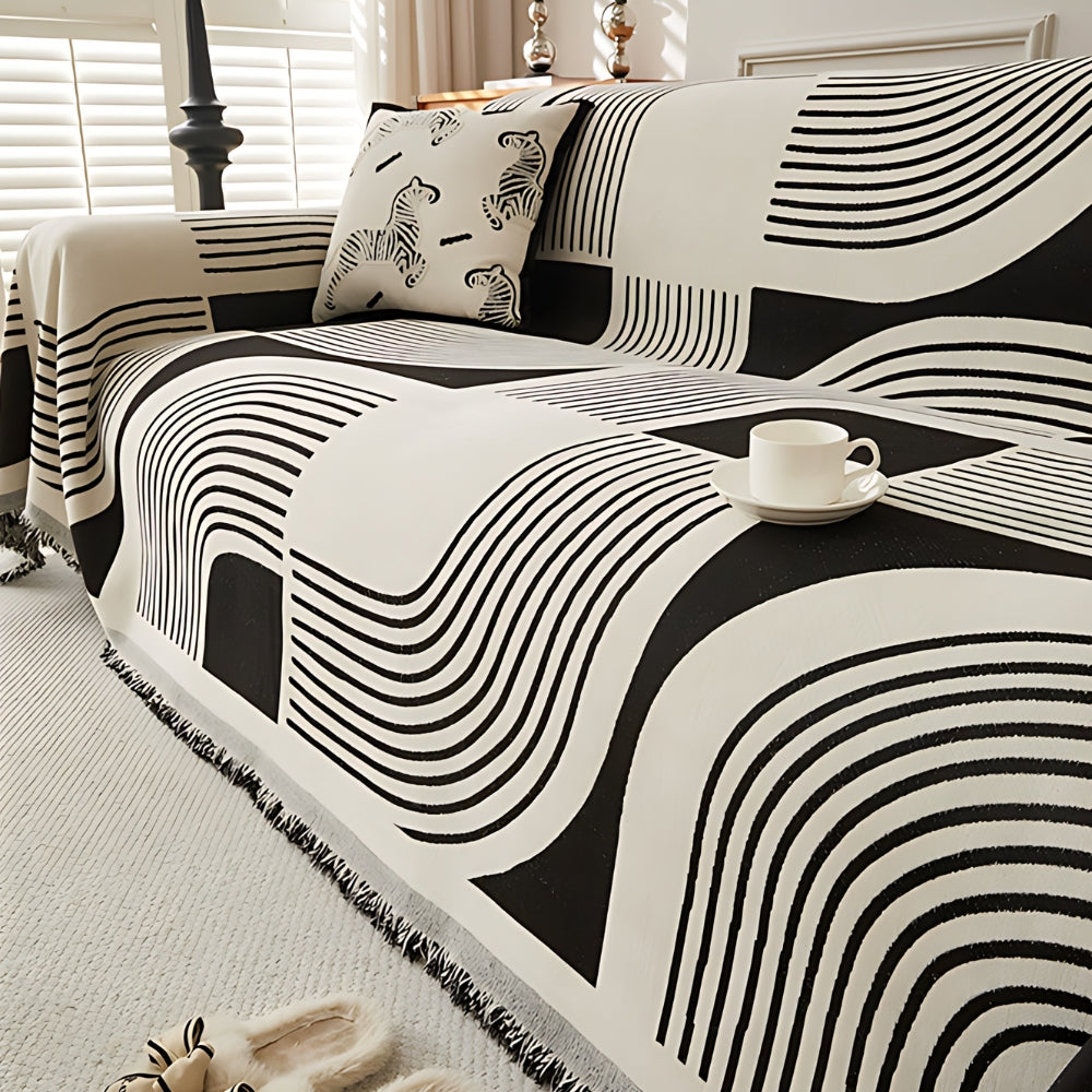 Modern geometric grey and white sofa cover with abstract wave pattern and fringe edges – washable couch slipcover for living room furniture protection