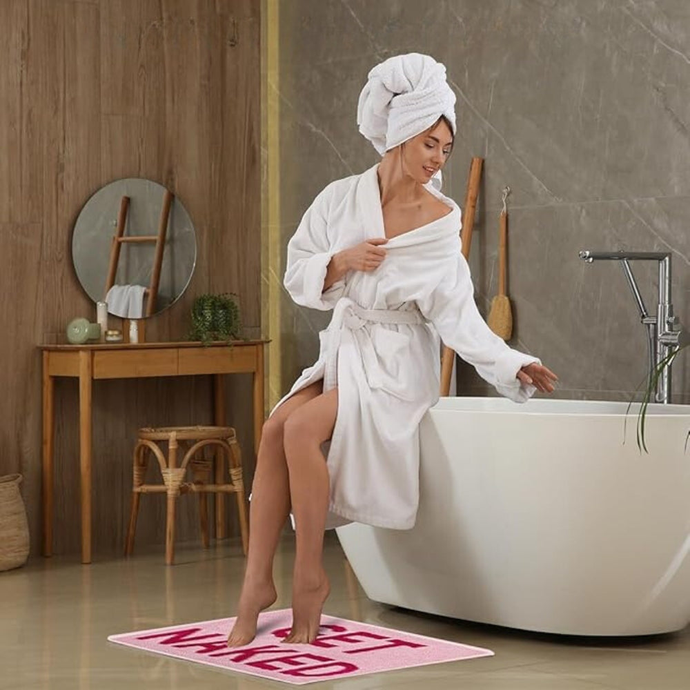 Pink bath mat with bold red ‘Get Naked’ lettering, soft absorbent funny bathroom rug for modern decor