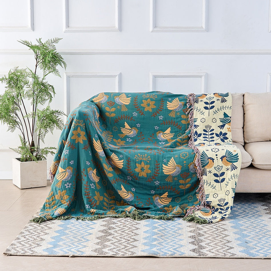 Bohemian sofa throw blanket with teal background, bird and floral patterns, and fringe edges, decorative couch cover for living room