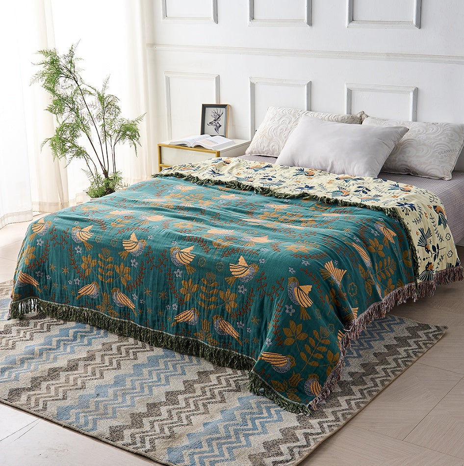 Bohemian sofa throw blanket with teal background, bird and floral patterns, and fringe edges, decorative couch cover for living room