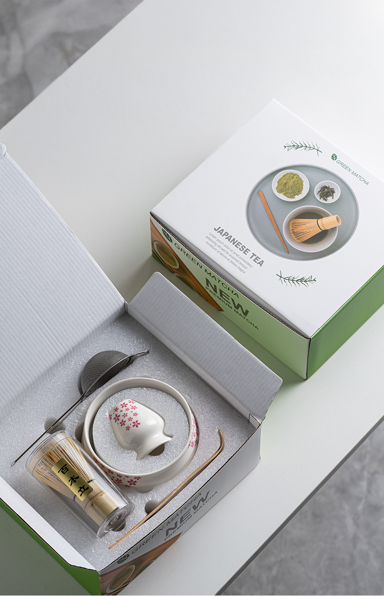 Japanese matcha set with white ceramic tea bowl and pink cherry blossom design, bamboo whisk, sifter, and tea scoop for traditional tea ceremony
