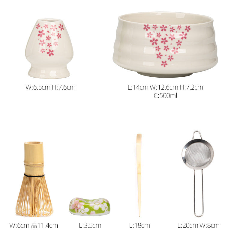 Japanese matcha set with white ceramic tea bowl and pink cherry blossom design, bamboo whisk, sifter, and tea scoop for traditional tea ceremony