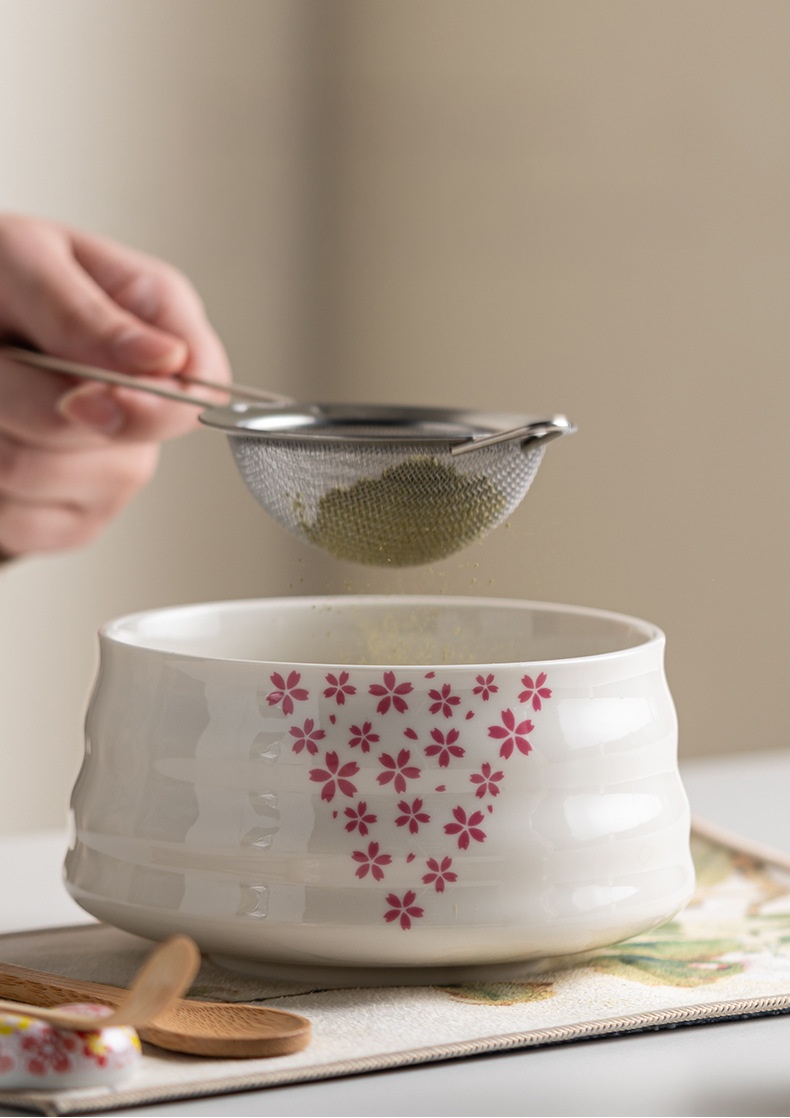 Japanese matcha set with white ceramic tea bowl and pink cherry blossom design, bamboo whisk, sifter, and tea scoop for traditional tea ceremony